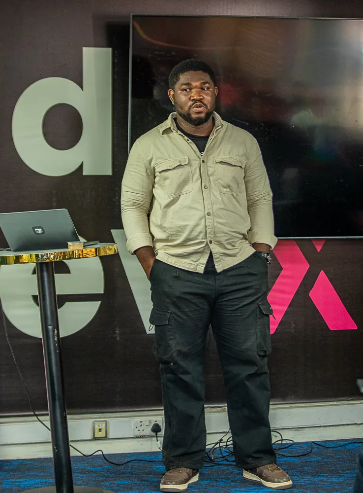 A presenter speaking beside a screen